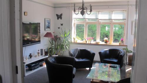 a living room with chairs and a table and windows at Guesthouse Sharon Aarhus in Aarhus