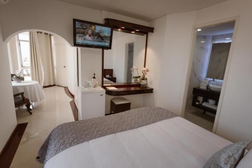a bedroom with a bed and a tv on the wall at Hotel Arenal in Santa Cruz de la Sierra