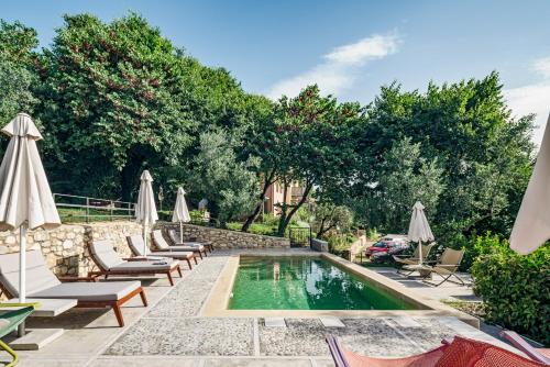 uma piscina com espreguiçadeiras e guarda-sóis em Mazaraki Guesthouse em Mystras