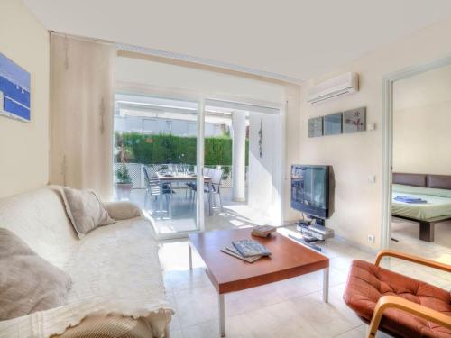 ein Wohnzimmer mit einem Sofa, einem TV und einem Tisch in der Unterkunft Apartment Nautic by Interhome in Platja  d'Aro