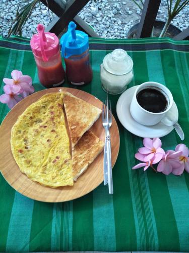 a table with a plate of food and a cup of coffee at Ombak Homestay in Gili Trawangan