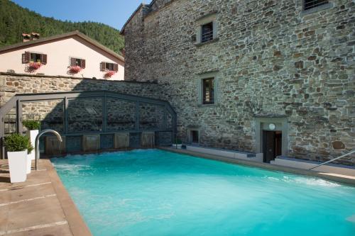 a large swimming pool in front of a stone building at Hotel Delle Terme Santa Agnese in Bagno di Romagna