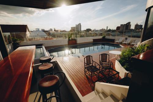 a rooftop deck with chairs and a pool on a building at Hotel Arenal in Santa Cruz de la Sierra