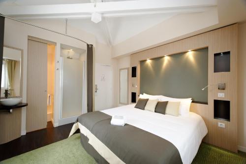 a hotel room with a large bed and a bathroom at Castel Victoria in Le Touquet-Paris-Plage