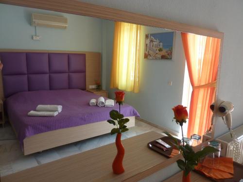 een slaapkamer met een paars bed en een grote spiegel bij Hotel White Rose Beach in Olympiakí Aktí