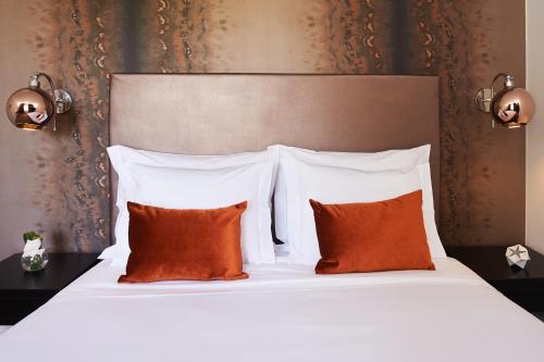 a bedroom with a white bed with orange pillows at Convento do Seixo Boutique Hotel & Spa in Fundão