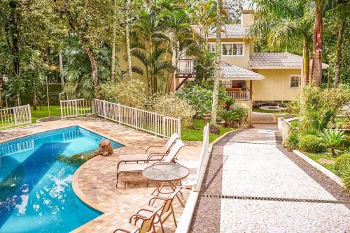 a swimming pool with a table and chairs next to a house at Chácara Familiar Próximo a Buffets in Mairiporã