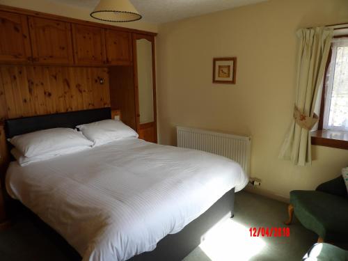 a bedroom with a white bed and a window at Glen Croft Cottage in Invermoriston