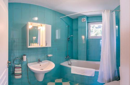 a blue tiled bathroom with a sink and a bath tub at Villa White Dove in Golden Sands