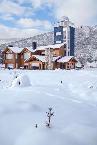 a building in the snow with a tree in the foreground at Galileo Boutique Hotel in San Carlos de Bariloche
