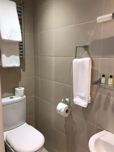 a bathroom with a toilet and a sink and towels at Coleman Apartment in Wolverhampton
