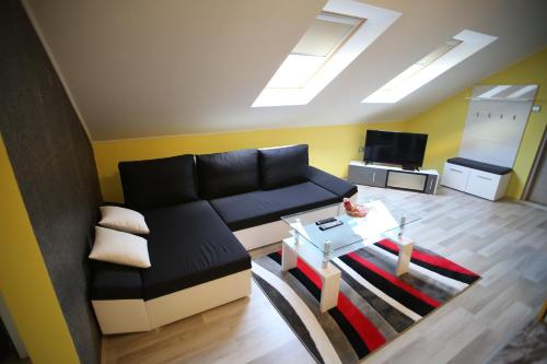 a living room with a black couch and a table at Centrum Lux 2 Apartmanok in Kaposvár