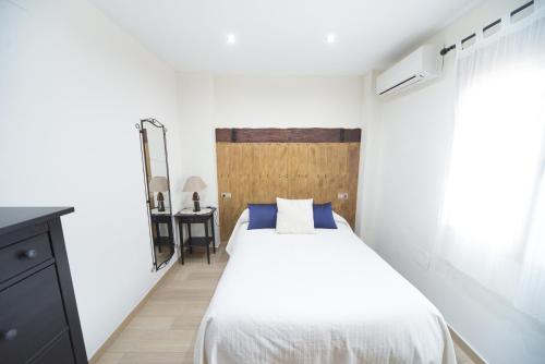 a bedroom with a white bed and a wooden headboard at Los Toneles in Puerto de Santa Cruz