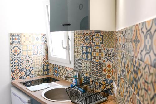 La salle de bains est pourvue d'un lavabo et d'un comptoir avec du carrelage. dans l'établissement Studio les Hortensias, à Avignon