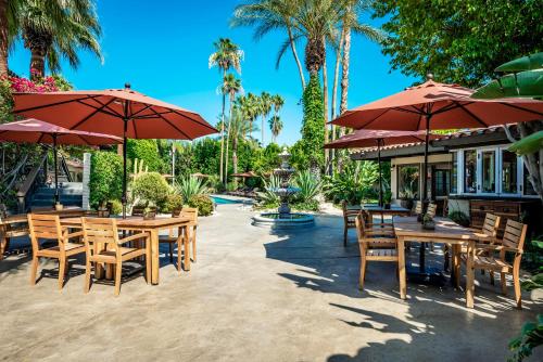 a patio with tables and chairs and umbrellas at Santiago Resort - Palm Springs Premier Gay Men’s Resort in Palm Springs