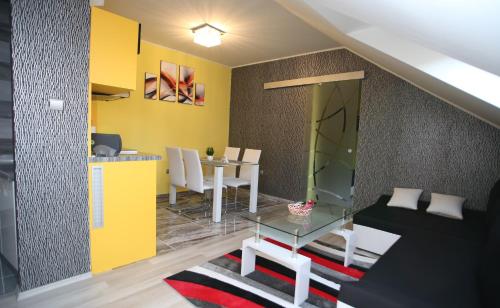 a living room with a table and a yellow wall at Centrum Lux 2 Apartmanok in Kaposvár