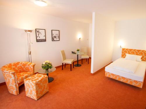 a hotel room with a bed and a chair at Hotel Birkenhof Therme in Bad Griesbach