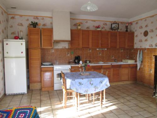 a kitchen with a table and a white refrigerator at Gîte des Géraniums in Crestet