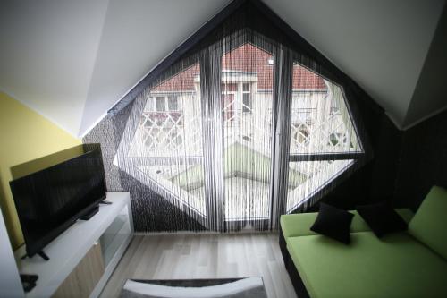 a living room with a green couch and a large window at Centrum Lux 2 Apartmanok in Kaposvár