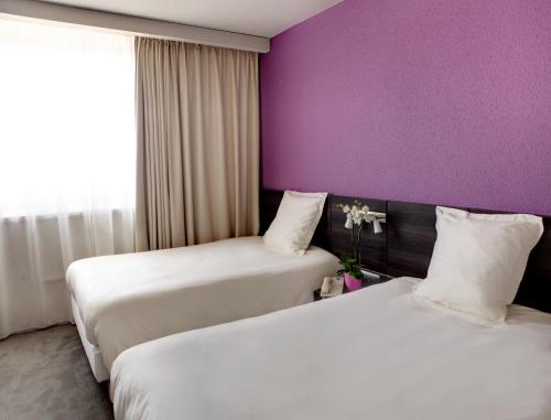 two beds in a hotel room with purple walls at Best Western Alexander Park Chambéry in Chambéry