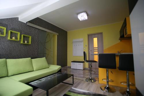 a living room with a green couch and a table at Centrum Lux 2 Apartmanok in Kaposvár