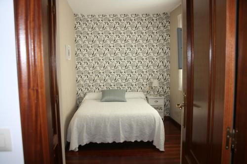 ein kleines Schlafzimmer mit einem weißen Bett mit einer Wand in der Unterkunft Casa Xa Abreu VUT-CO-002490 in Padrón