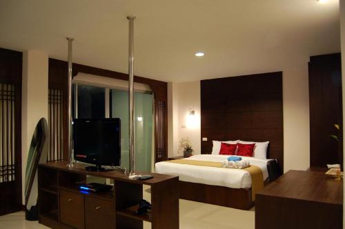 a bedroom with a bed and a flat screen tv at Baan Manthana Hotel, Hua Hin in Hua Hin