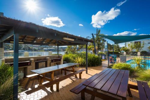 a picnic table and bench on a patio at Sails Luxury Apartments Merimbula in Merimbula