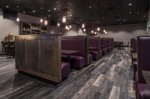 a dining room with purple chairs and a bar at Astoria Hotel & Event Center in Dickinson