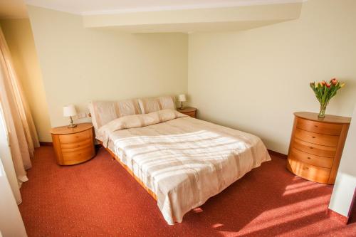 una camera da letto con un letto e due cassettiere con sopra dei fiori di AirInn Vilnius Hotel a Vilnius