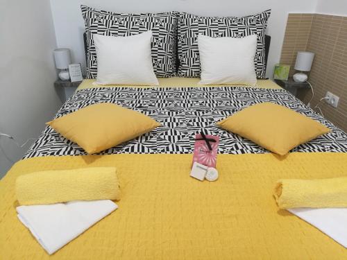 a bed with yellow and white pillows and a pair of shoes on it at Flumine in Rijeka