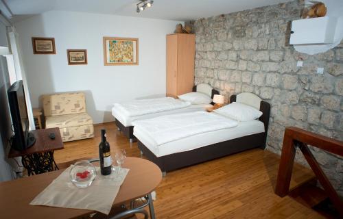Una habitación con dos camas y una mesa con una botella de vino. en Apartment Old Town Gverovic, en Dubrovnik