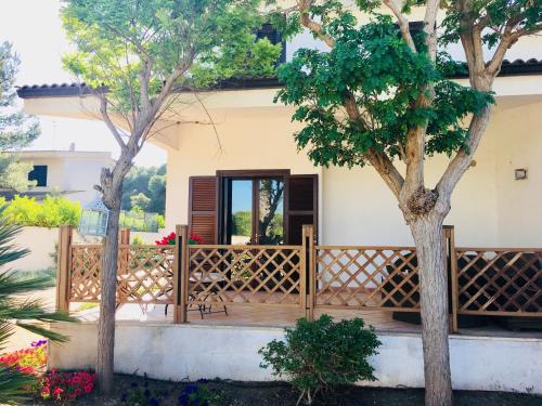 a house with a wooden porch with two trees at Villa Lido Silvana Marina di Pulsano in Pulsano