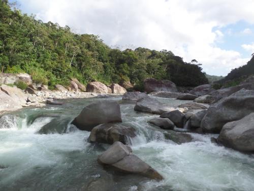 a river with rocks in the middle of a mountain at Hotel Rio in La Ceiba
