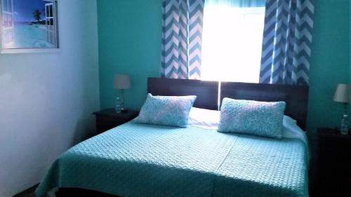 a bedroom with a bed with two pillows and a window at Bailey's Bed and Breakfast in Runaway Bay
