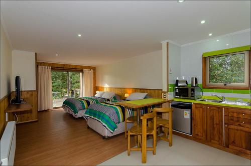a bedroom with two beds and a kitchen with a sink at Hotel Boutique Ecoterraverde in Panguipulli