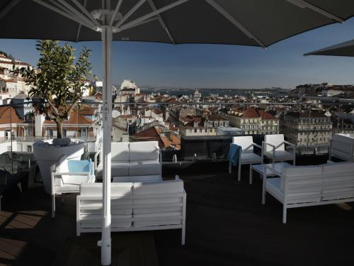 a balcony with white chairs and an umbrella at Hotel Mundial in Lisbon