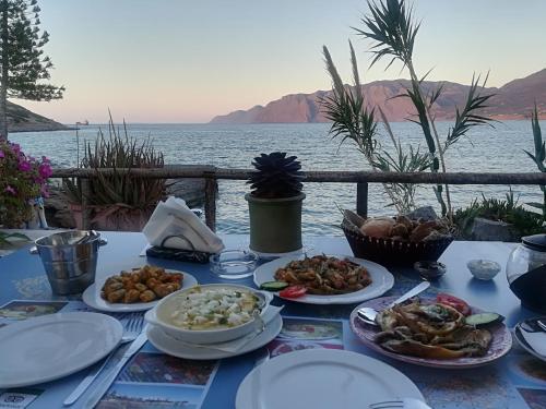 a table with plates of food on it next to the water at Mochlos Beach Villa Seafront house in Mochlos
