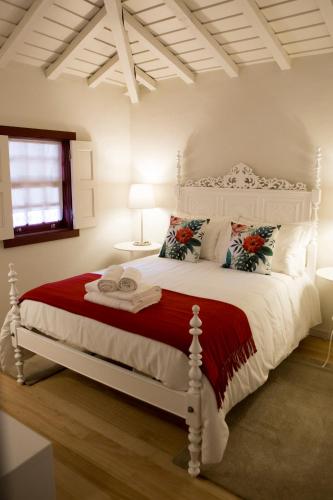 a bedroom with a white bed with a red blanket at Casa da Teresina in Sistelo