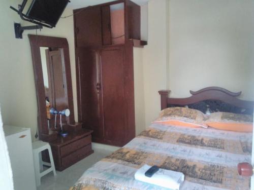 a bedroom with a bed with a dresser and a television at Hotel Josemar in El Espinal