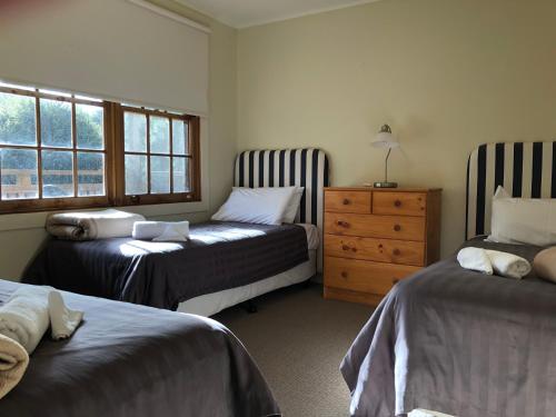 a bedroom with two beds and a dresser and a window at Corinna Wilderness Village in Corinna