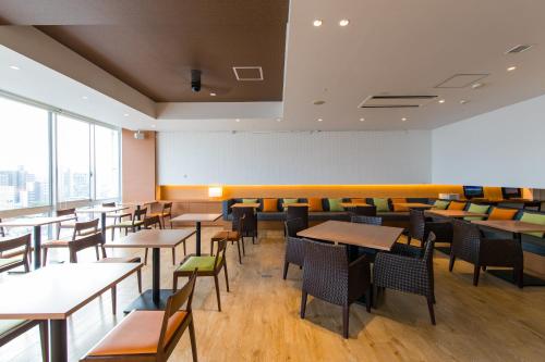 a dining room with tables and chairs and windows at JR Kyushu Hotel Miyazaki in Miyazaki