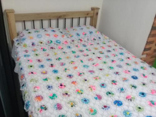 a bed with a flower quilt on it at Hotel Atenas Jericó in Jericó