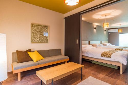 a hotel room with two beds and a couch at Bijou Suites Kakomi in Osaka