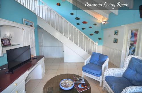a living room with a staircase with a tv and blue walls at Moon San Villa at the Blue Lagoon in Port Antonio