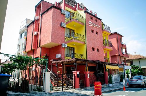 a red and yellow building on the side of a street at Виктория Созопол in Sozopol