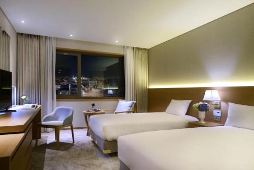 Pokój hotelowy z 2 łóżkami i biurkiem w obiekcie Astar Hotel w mieście Czedżu