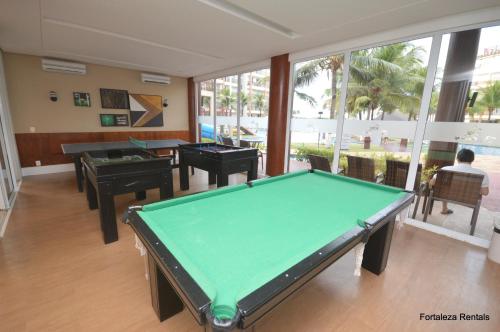 a pool table in a room with tables and windows at Beach Living Apartment in Aquiraz