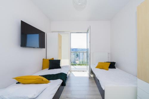 グダニスクにあるFeel Summer Vibes At 3BR Panoramic View Apartmentのベッド2台、壁掛けテレビが備わる客室です。