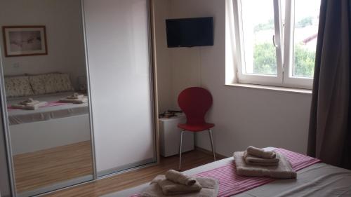 a bedroom with a red chair and a mirror at Nina Villa in Rab